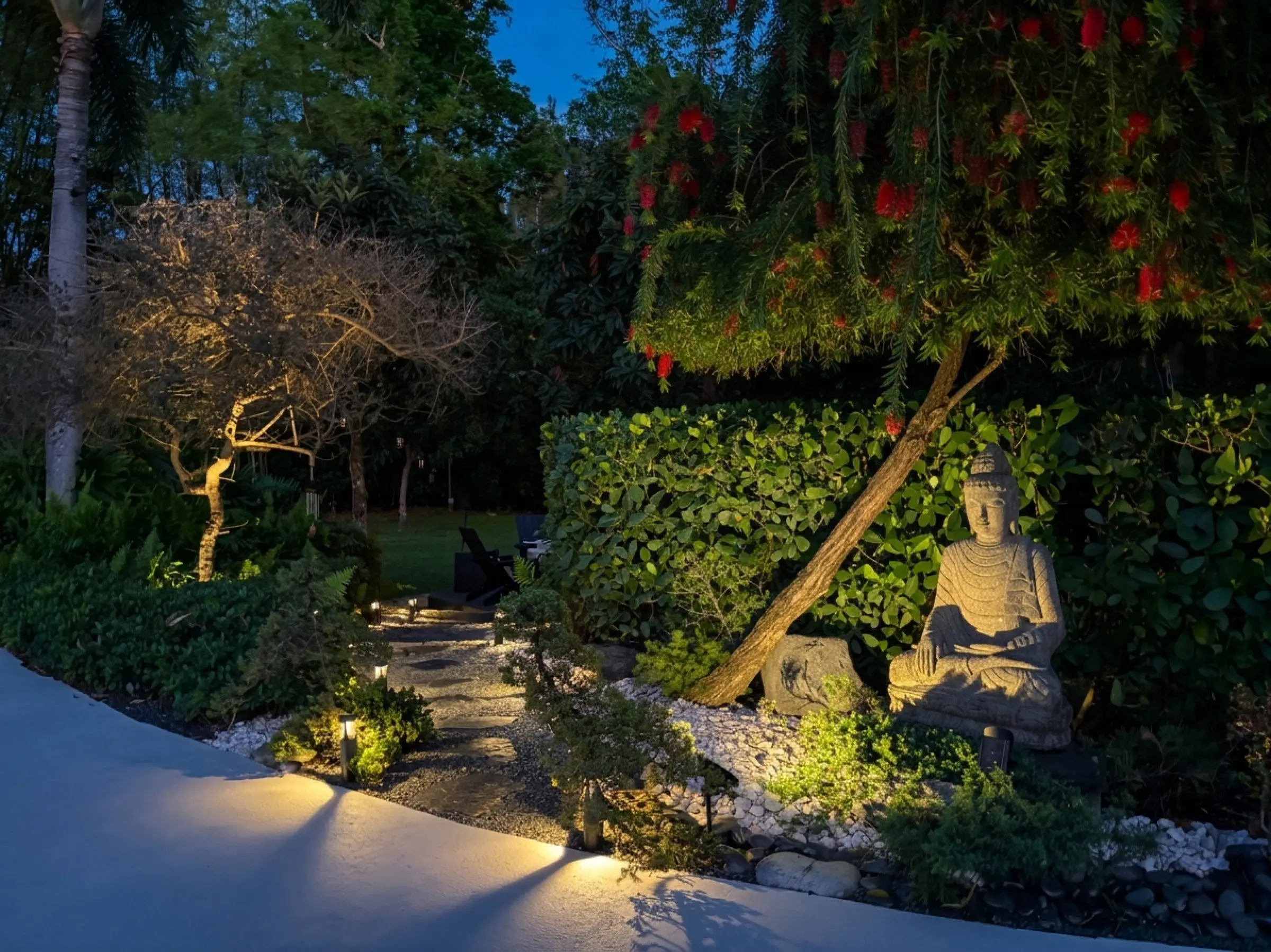 Pool at night with Buddha sculpture and landscape lighting reflected in water